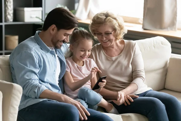 Happy different generations family using smartphone at home. — Stock fotografie