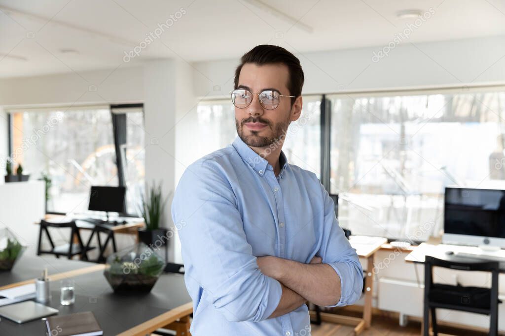 Pensive business man wearing glasses, posing with hands folded