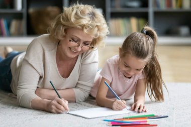 Happy middle aged older woman drawing with small girl.