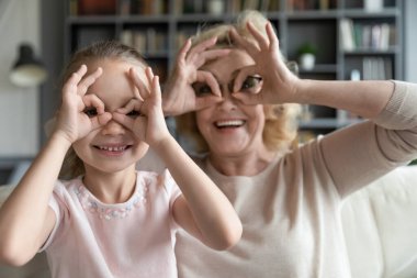 Happy small 7s kid girl making funny grimaces with granny.