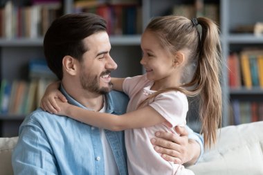 Affectionate caring young smiling father cuddling little daughter.