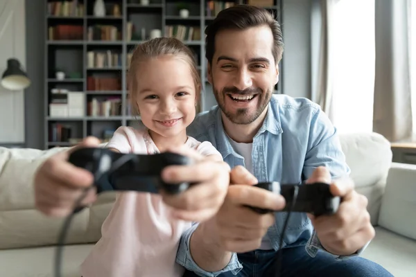 Happy small 7s kid girl playing online video games with young father. — Photo