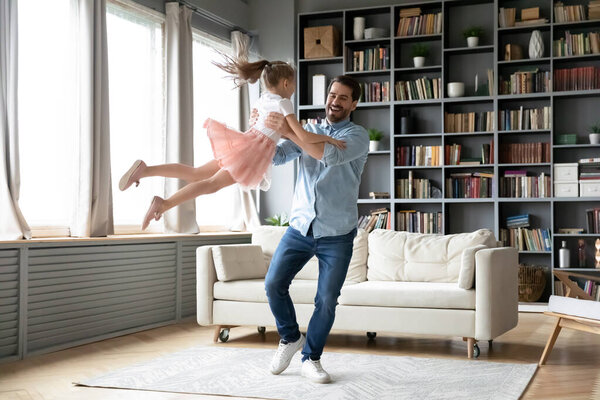 Happy young father lifting in air laughing small kid daughter.
