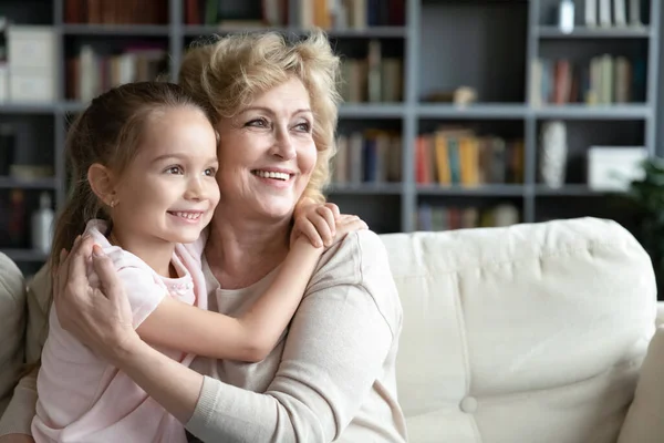 Smiling little girl cuddling loving caring older middle aged grandmother. — Foto de Stock