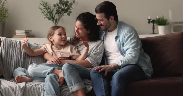 Liebevolle Eltern im Gespräch mit kleiner Tochter sitzen zusammen auf Couch — Stockvideo