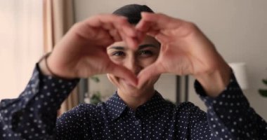 İçten gülümseyen genç melez Hintli kadın aşk sembolü gösteriyor..