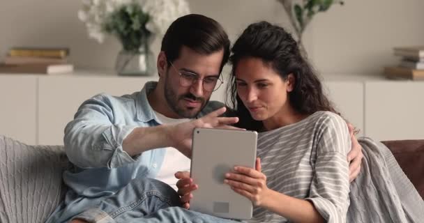 Jeune couple marié se détendre sur le canapé à l'aide d'un appareil tablette — Video