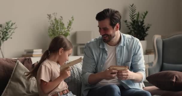 Kleine dochter en vader die thuis een speelgoedpistool afschieten — Stockvideo