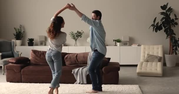 在舒适的现代客厅里快乐地跳舞的年轻夫妇 — 图库视频影像