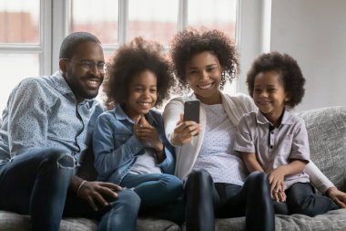 Mutlu Afro-Amerikan ailesi telefonda selfie çekiyor.