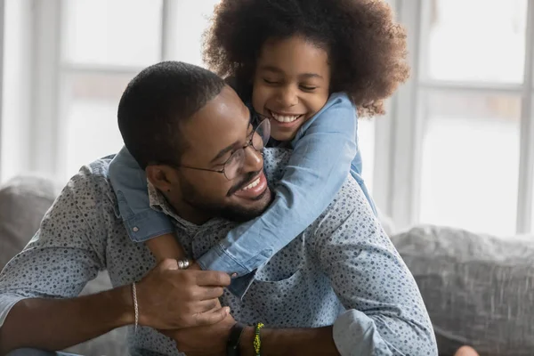 Close-up lachende Afro-Amerikaanse vader piggy backing schattig dochter — Stockfoto