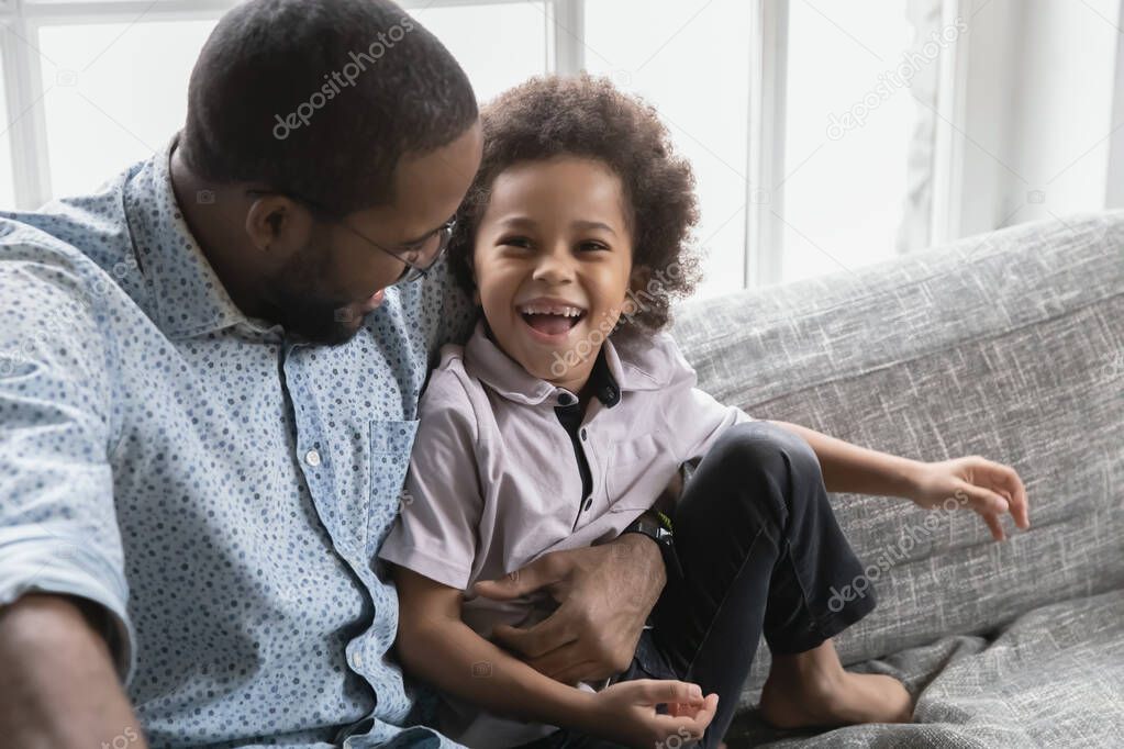 Close up African American father and son hugging, having fun