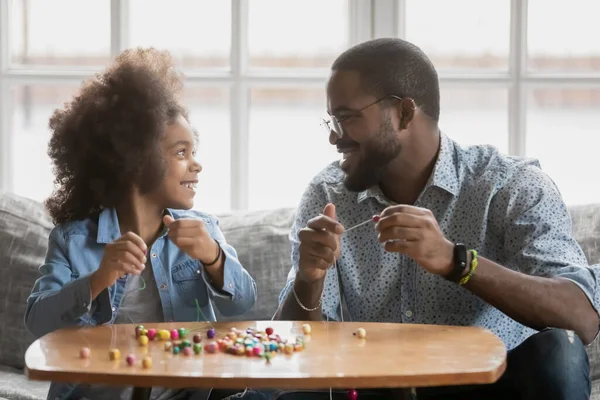 Nahaufnahme afroamerikanischer Mann und Tochter, die mit Perlen spielen — Stockfoto