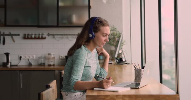 Mujer de 25 años motivada en auriculares escuchando conferencia educativa en línea. — Vídeo de stock