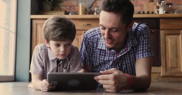 Fürsorglicher junger Vater zeigt interessiertem kleinen Sohn Bewerbungen. — Stockvideo