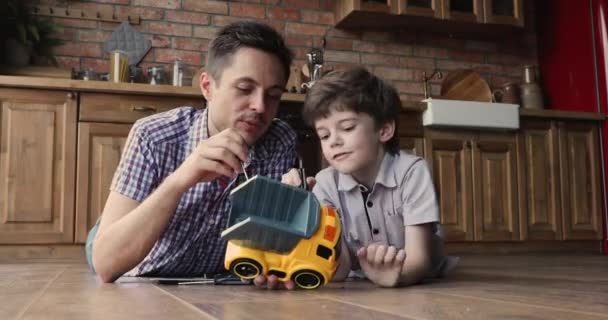 Pečující mladý otec výuka malý syn opravy hračka auto. — Stock video