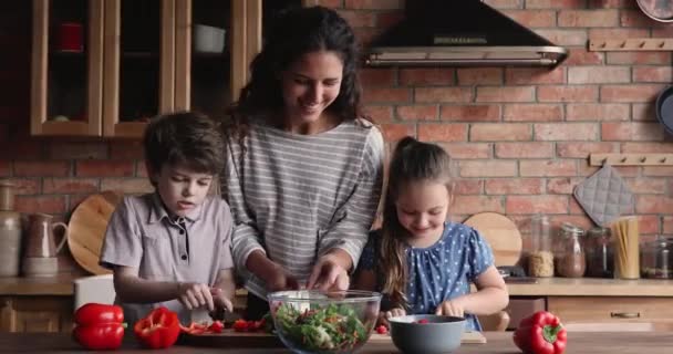 Sonriente hermosa madre joven enseñando a los niños a preparar comida. — Vídeos de Stock