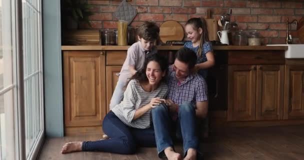 Verspielte kleine Jungen und Mädchen kitzeln lachende Eltern. — Stockvideo