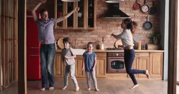 Overjoyed pais descalços pulando com crianças na cozinha. — Vídeo de Stock