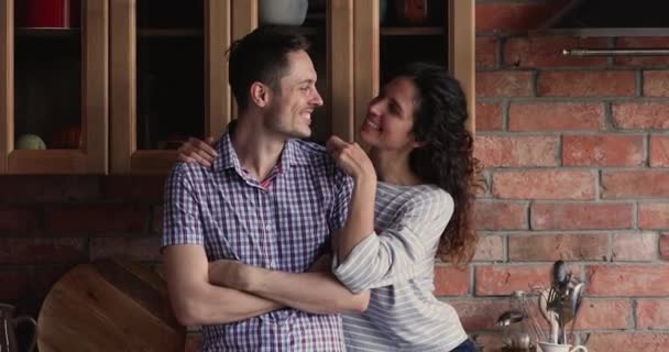 Счастливая молодая семейная пара обнимается на отремонтированной кухне. — стоковое видео