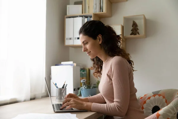 Femme millénaire souriante engagée dans le travail par ordinateur portable à la maison — Photo