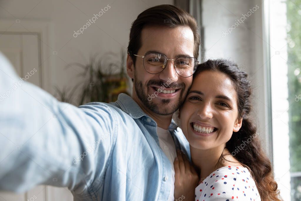 Millennial couple in love cuddling taking selfie at new house.