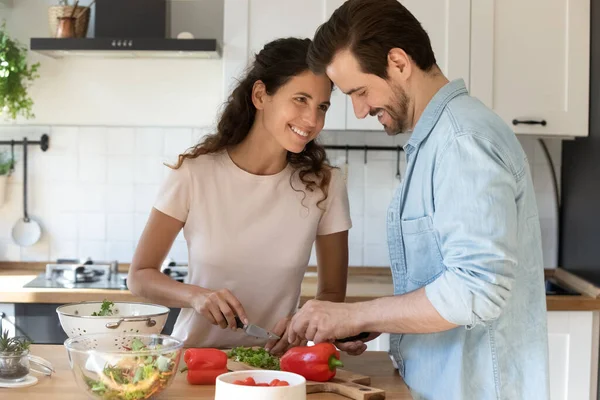 Positive junge Eheleute kochen Essen und genießen angenehme Gespräche in der Küche — Stockfoto