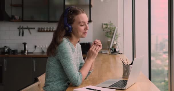 Mujer milenaria sonriente en auriculares con conversación de videollamada. — Vídeos de Stock
