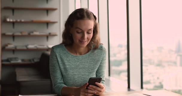 Usmívající se tisíciletá atraktivní žena používající mobilní aplikace uvnitř. — Stock video