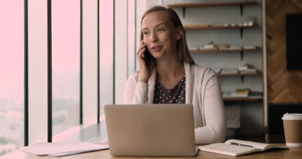 Gyönyörű fiatal képzett eladó beszél mobilon, dolgozik a számítógépen. — Stock videók