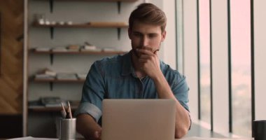 Bilgisayar üzerinde çalışan odaklanmış genç bir adam.