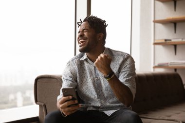 Heyecanlı genç Afrikalı adam lotoyu izliyor ve ikramiyeyi kutluyor