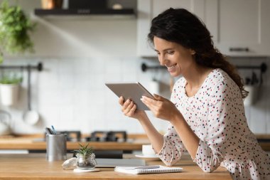 Gülümseyen kadın evde tablet kullanıyor.