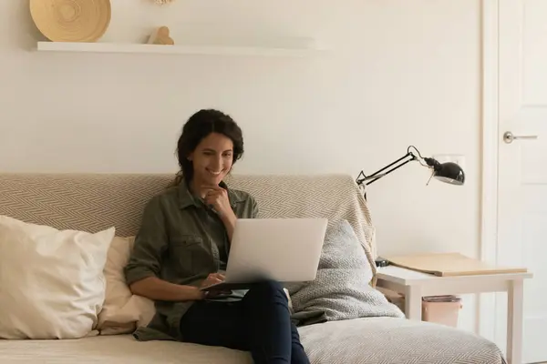 Lächelnde Frau nutzt Laptop, um Video zu Hause anzusehen — Stockfoto
