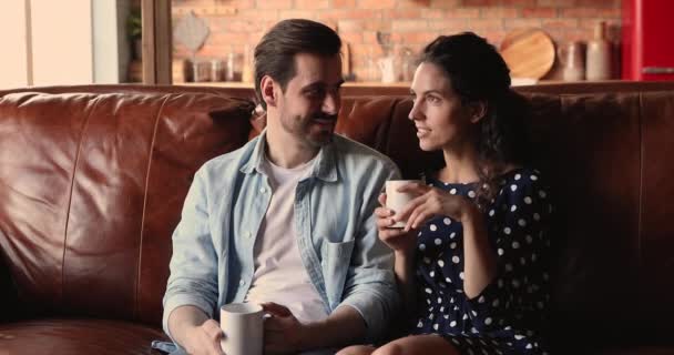 Par i kärlek pratar avkopplande på soffan med kaffekoppar — Stockvideo