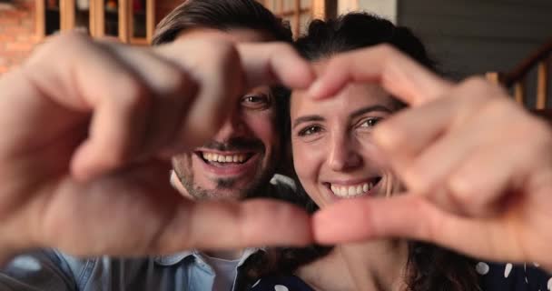 Χαρούμενα πρόσωπα ζευγαριών που κοιτάζουν μέσα από ενωμένα δάχτυλα κάνοντας σχήμα καρδιάς — Αρχείο Βίντεο