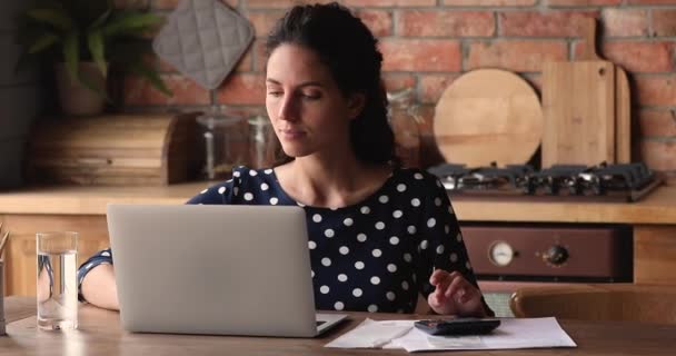 Femme sérieuse calcule les dépenses mensuelles sur la calculatrice — Video