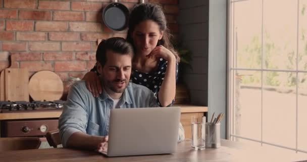 Молодая пара с помощью ноутбука покупает он-лайн услуги — стоковое видео