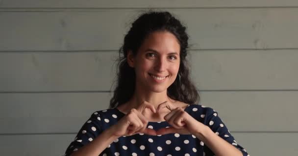 Mujer sonrisa mira a la cámara mostrando la forma del corazón con los dedos — Vídeos de Stock