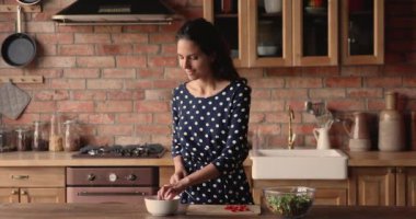 Mutfakta duran bir kadın sebze salatası için vişneli domates kesiyor.