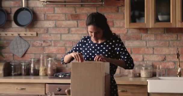 Женщина, открывающая коробку с посылкой, чувствует радость и удовлетворение — стоковое видео