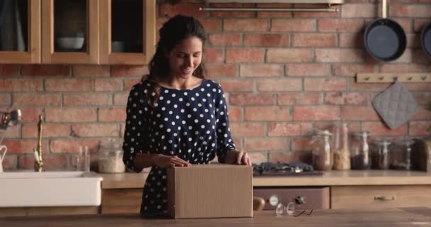 Vrouw opent pakket doos controleren bestelde online goederen voelt zich tevreden — Stockvideo