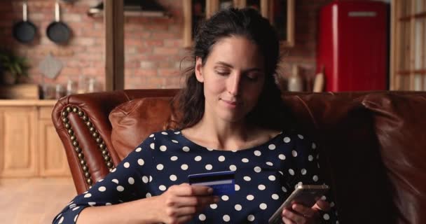 Женщина со смартфоном вводит данные кредитной карты, покупая онлайн — стоковое видео