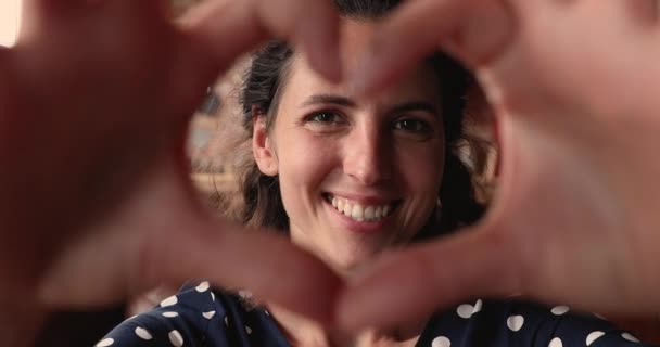 Mujer hace con dedos corazón forma sonrisa mirada a cámara — Vídeos de Stock