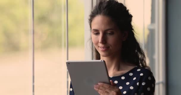 Ładna młoda kobieta stojąca wewnątrz za pomocą tabletu — Wideo stockowe