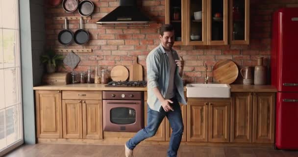 Мужчина танцует босиком на кухне на теплом деревянном полу — стоковое видео
