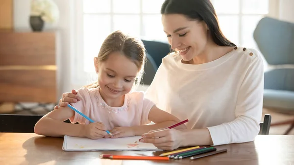 Leende mamma och liten dotter målar i album hemma — Stockfoto