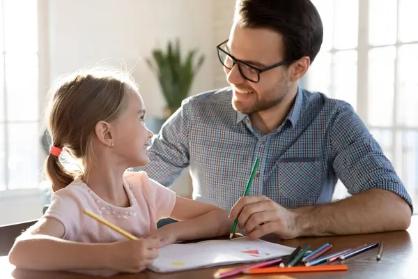 Smiling dad and little daughter drawing together
