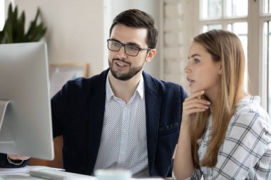 Birlikte bilgisayar başında çalışan ve fikirleri tartışan yöneticiler.