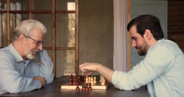 Szczęśliwy 60s stary Dojrzały mężczyzna cieszy się gra w szachy z synem. — Wideo stockowe